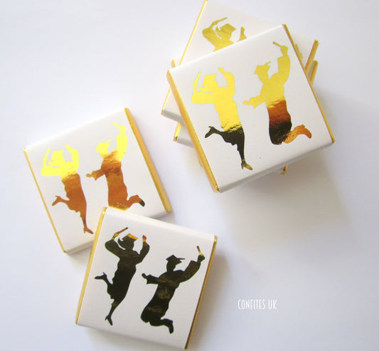 Square Fairtrade milk chocolate favour (approx 3 × 3 cm, 5 g) wrapped in white glossy paper with gold ‘Happy Graduates’ script, personalised message on back, pack of 25