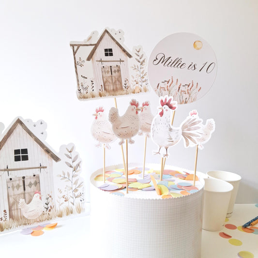A personalized farm cake topper set that includes a barn, a rooster, and chickens.
 The set features a name-and-age topper and a freestanding barn figure.