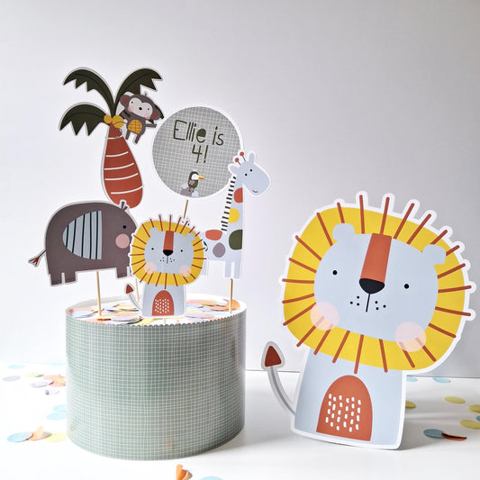 A handmade cake topper set from the UK featuring a lion, giraffe, elephant, and monkey, along with a custom name and age topper.