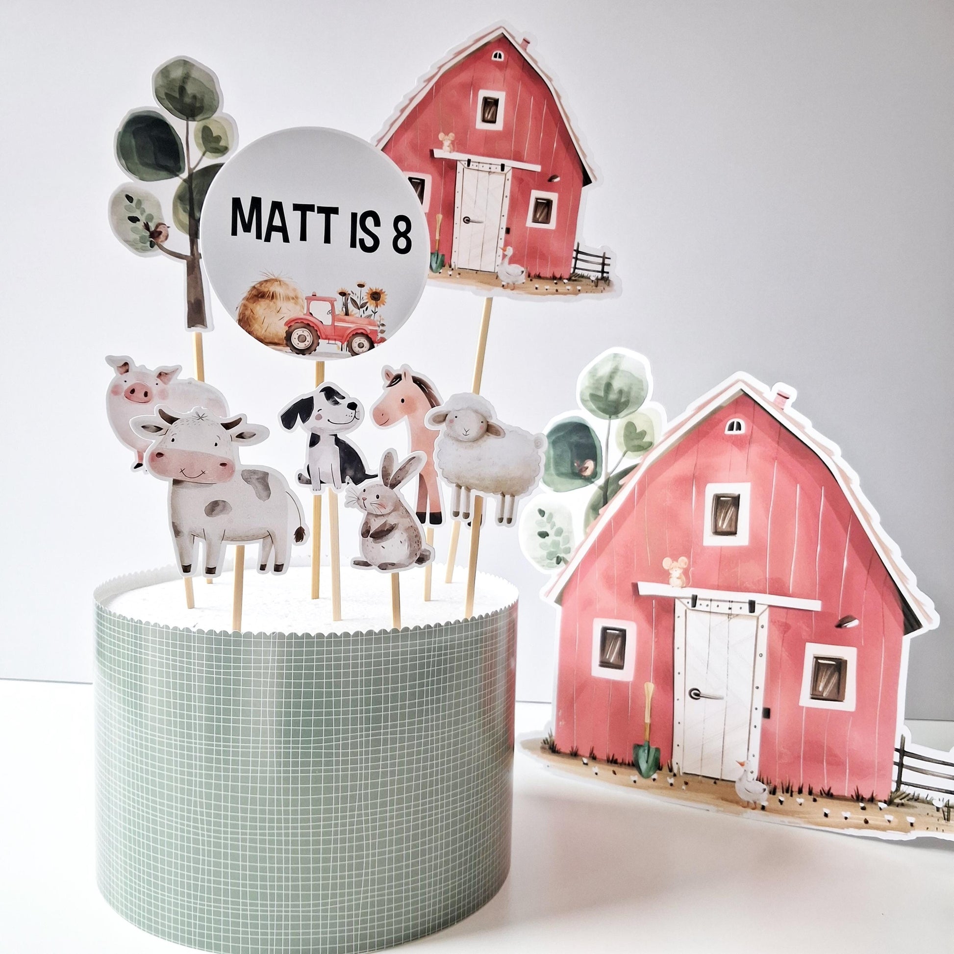 A personalized farmyard cake topper set that includes a red barn and various farm animals.