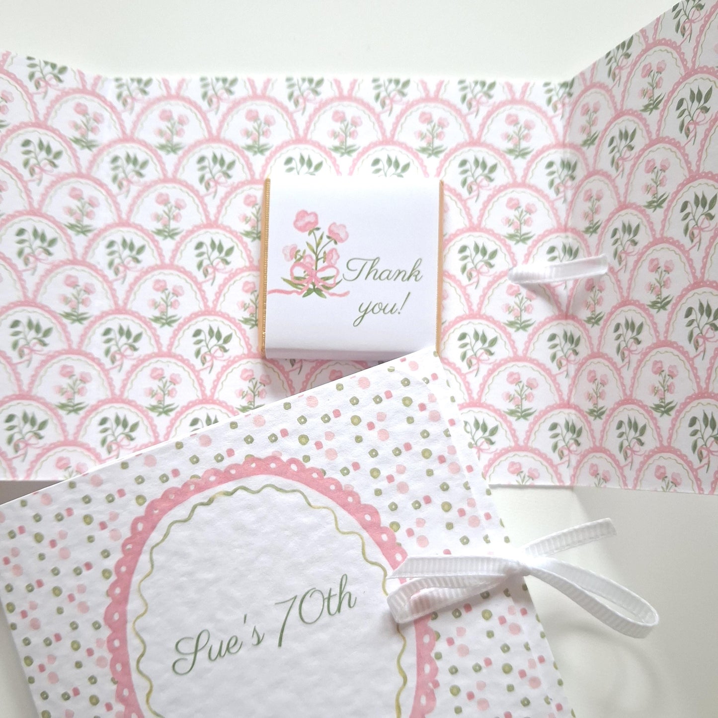 Handmade, personalized birthday favours featuring a pink floral design. They include a ribbon and a chocolate treat.