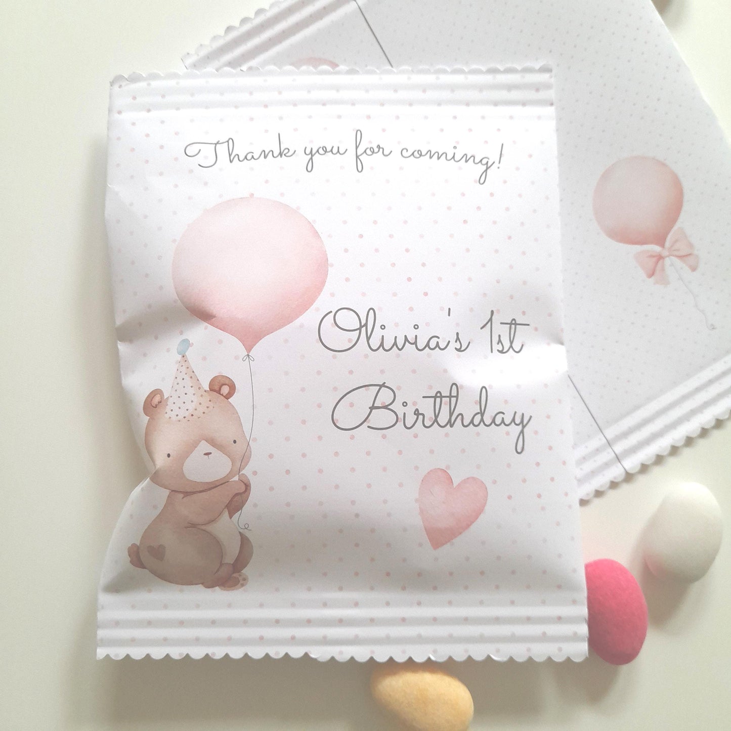 personalized favour bags, featuring a baby bear theme, for a 1st birthday party. They are designed for party guest treats and table decor.