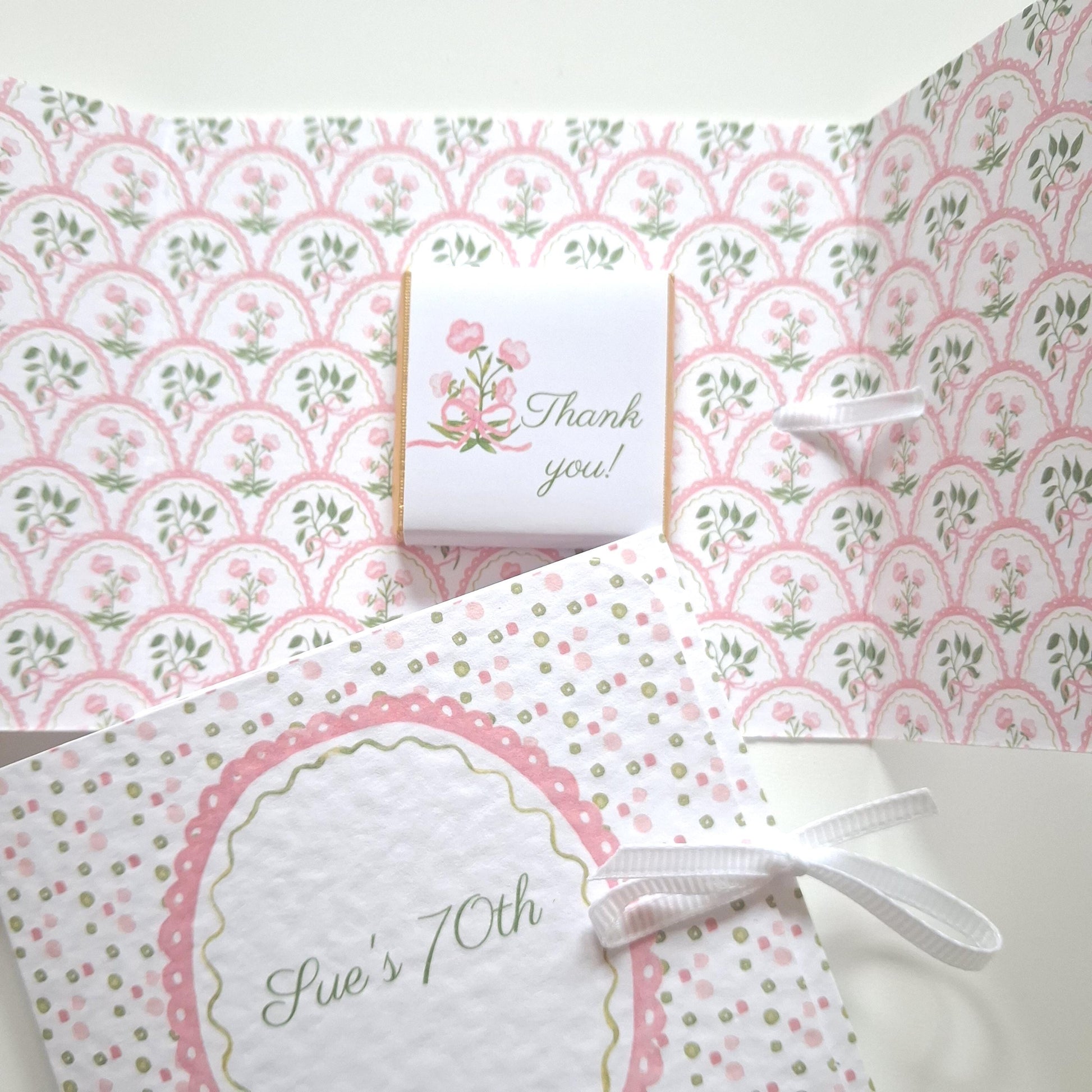 Handmade, personalized birthday favours featuring a pink floral design. They include a ribbon and a chocolate treat.